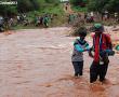  Cashing in on the floods. This young man assists a stranded resident in crossing the flooded Dzindi River. He charges R10 a trip. Photo: Elmon Tshikhudo.